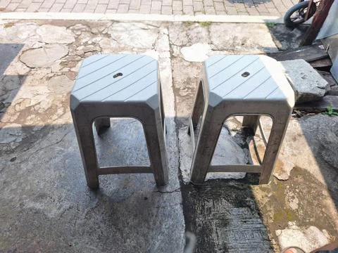Two simple white plastic chairs that are commonly owned by street vendors Stock Photos