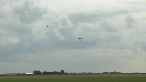 Two single Skydivers with open Parachutes slowely glide down to earth. The Stock Footage 162569378