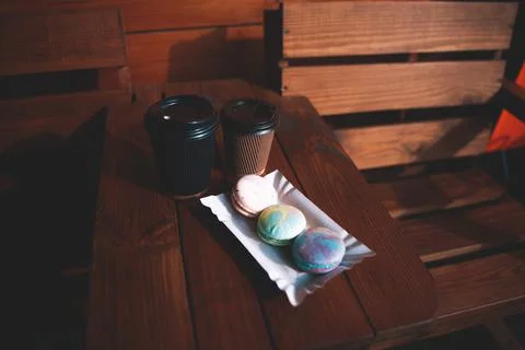 Two single use disposable cups with coffee and macarons on the wooden table Stock Photos