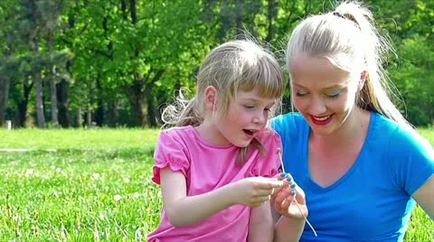Two sister blowing dandelion in the park slow motion Stock Footage 24673498