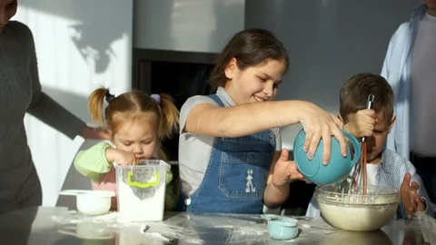 Two sisters 2 and 9 years old and a brother of 6 years knead the dough in the Stock Footage 86810877