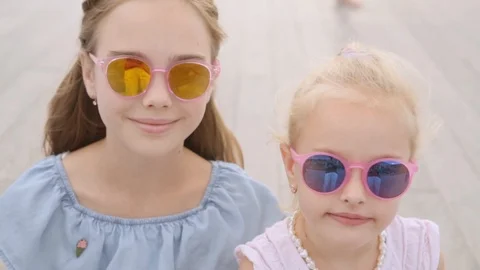 Two sisters 5 and 10 years in in mirror glasses looks at camera, close up Stock Footage 120442757