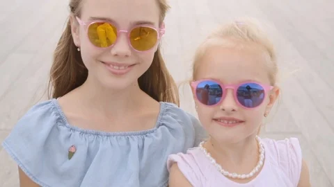 Two sisters 5 and 10 years in in mirror glasses looks at camera, close up Stock Footage 120442796
