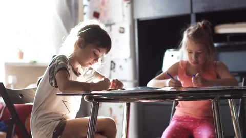 Two sisters 6 and 7 years drawing together sitting at the table. children draw Stock Footage 81672146