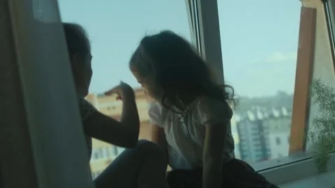 Two sisters are having fun, talking and looking through the window, sitting on Stock Footage 251732089