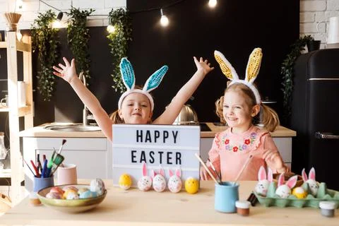 Two sisters are having fun while decorating Easter eggs at the kitchen, happy Stock Photos