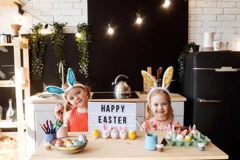 Two sisters are having fun while decorating Easter eggs at the kitchen, happy Stock Photos