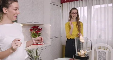 Two sisters are playing with fruit and preparing healthy smoothie In kitchen Stock Footage 145825624