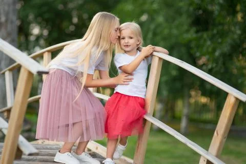 Two sisters are standing on wooden bridge in the park Stock Photos