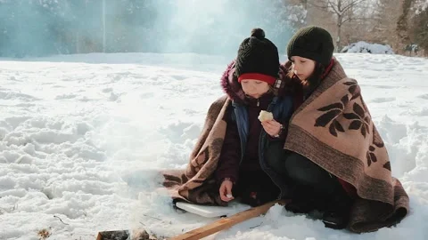 Two sisters bask by the fire in the winter park. Rest and unity with nature Stock Footage 146600574
