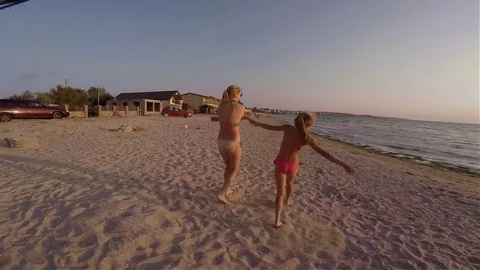Two sisters blondes in bikinis funny dance on the beach Video stock 74631537