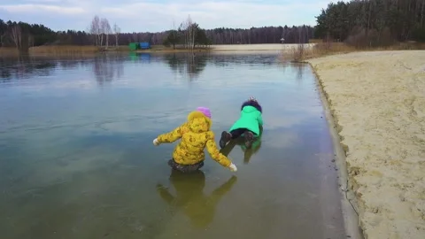 Two sisters crawl on the ice of the lake with an impernerable winter. Stock Footage 153492949
