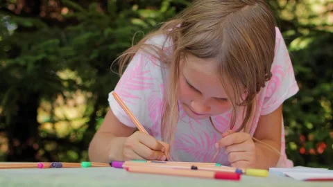 Two sisters drawing with fineliners in notebooks at a small table in a summ.. Stock Footage 304149091