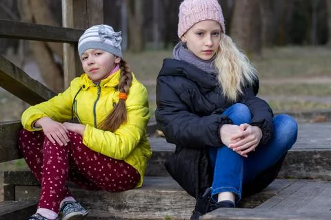 Two sisters drinking a refreshment sitting by the lake in the afternoon. Stock Photos