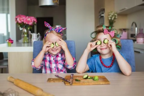Two sisters fool with a vegetable on a kitchen Stock Photos