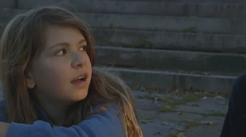 Two sisters having a conversation while sitting on some steps in a park Stock Footage 43798055