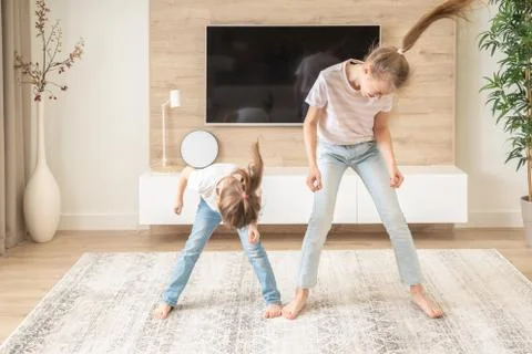 Two sisters having fun dancing in living room, happy family concept Stock Photos