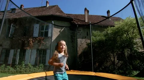 Two sisters, jumping on a trampoline in the courtyard of a village house Stock Footage 60030631