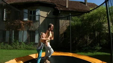 Two sisters, jumping on a trampoline in the courtyard of a village house Stock Footage 60030757