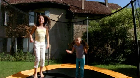 Two sisters, jumping on a trampoline in the courtyard of a village house Stock Footage 60030770