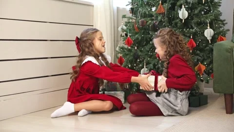 Two sisters, little girls pulling big wrapped gift box with red ribbon, fighting Stock Footage 314180872