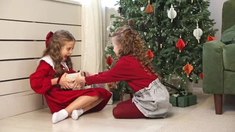 Two sisters, little girls pulling big wrapped gift box with red ribbon, fighting Stock Footage 314180887