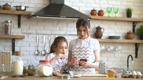 Two sisters looking recipe at the smartphone and cheking ingredients. Stock Footage 106412859