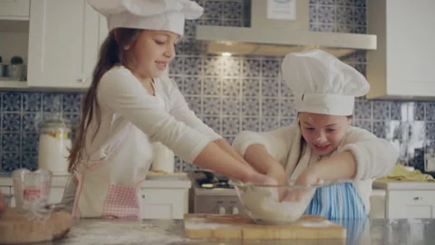Two sisters making dough in the kitchen by themselves Stock Footage 279742115