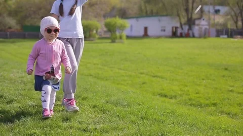 Two sisters play and run around the green grass Stock Footage 75531311