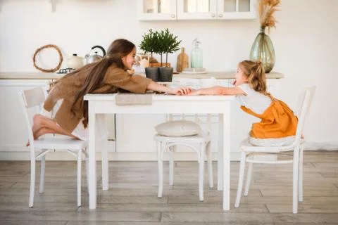 Two sisters play in a bright, stylish kitchen. Beautiful interior. Stock Photos