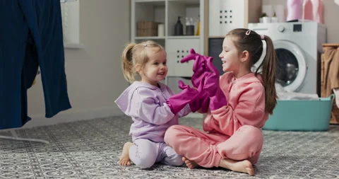 Two sisters play together while cleaning the apartment sit on the bathroom floor Stock Footage 201102133