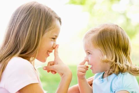 Two sisters playing outdoors and smiling Stock Photos