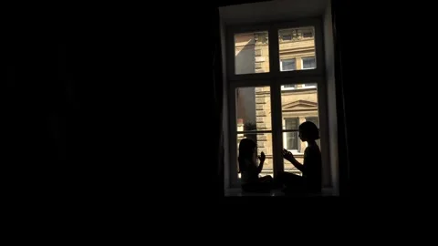 Two sisters playing palm games while sitting on the windowsill Stock Footage 274397619