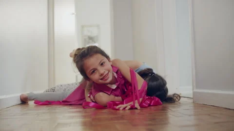 Two sisters playing with ribbon on the floor Stock Footage 279746409