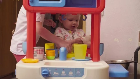 Two sisters playing in toy kitchen Stock Footage 77002616