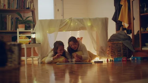 Two sisters playing under the blanket fort and laughing Stock Footage 279744174