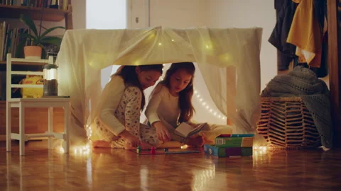 Two sisters playing under the blanket fort at home Stock Footage 279745263