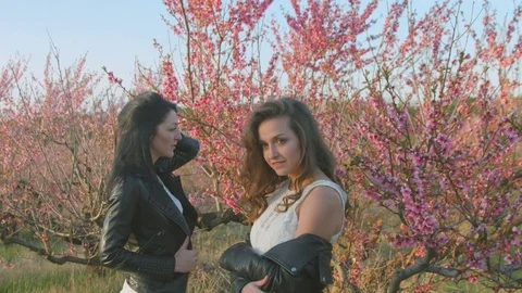 Two sisters posing while standing next to the flowering tree Stock Footage 78685240