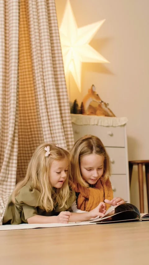 Two sisters reading a book lying in a kinds' play tent at Christmas time. Stock Footage 293287784