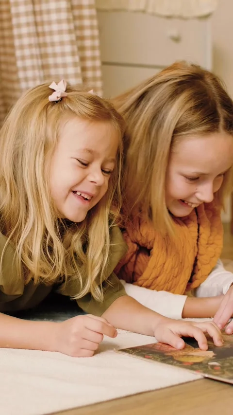 Two sisters reading a book lying in a kinds' play tent at Christmas time. Stock Footage 293287814