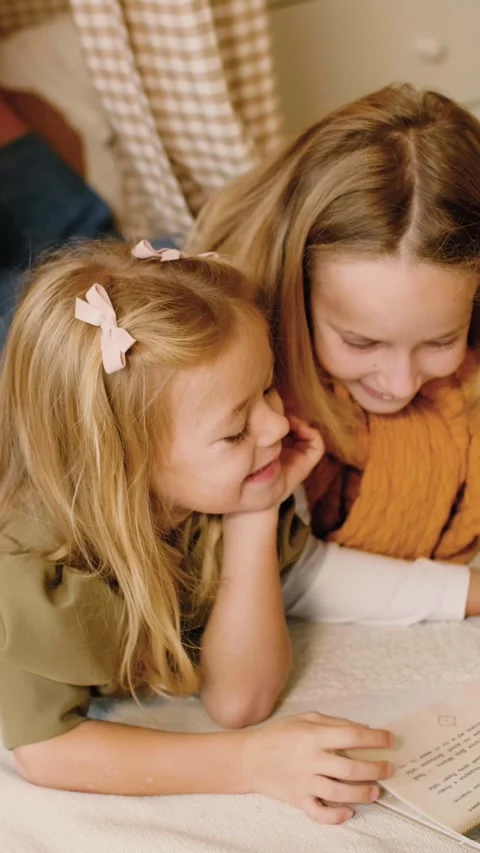 Two sisters reading a book lying in a kinds' play tent at Christmas time. Stock Footage 293287926
