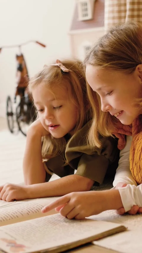 Two sisters reading a book lying in a kinds' play tent at Christmas time. Stock Footage 293288480
