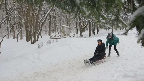 Two sisters ride mom sledding Stock Footage 72372908