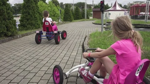 Two sisters ride small mechanical machines on a special track in Riga, the ca Stock Footage 153329192