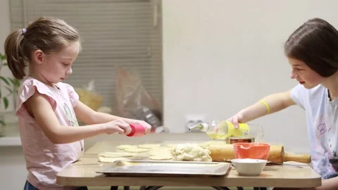 Two sisters roll out dough for cooking and baking homemade buns Stock Footage 167023996