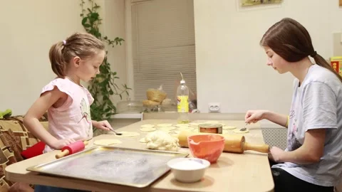 Two sisters roll out dough for cooking and baking homemade buns Video stock 167024100