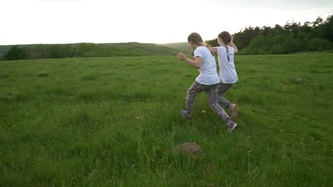 Two sisters running and having fun in meadow Stock Footage 98066088