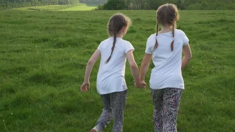 Two sisters running away in meadow and laughing Stock Footage 98065932