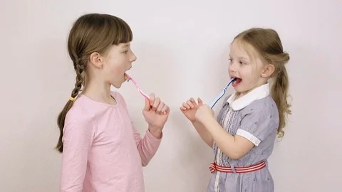 Two sisters show how to brush your teeth on a white background 動画素材 106443364