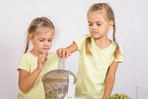 Two sisters squeezed fruit juice in a juicer Stock Photos
